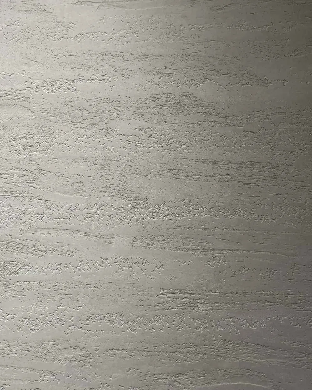 Close-up of gray Travertino Venetian plaster with horizontal bands and open pores