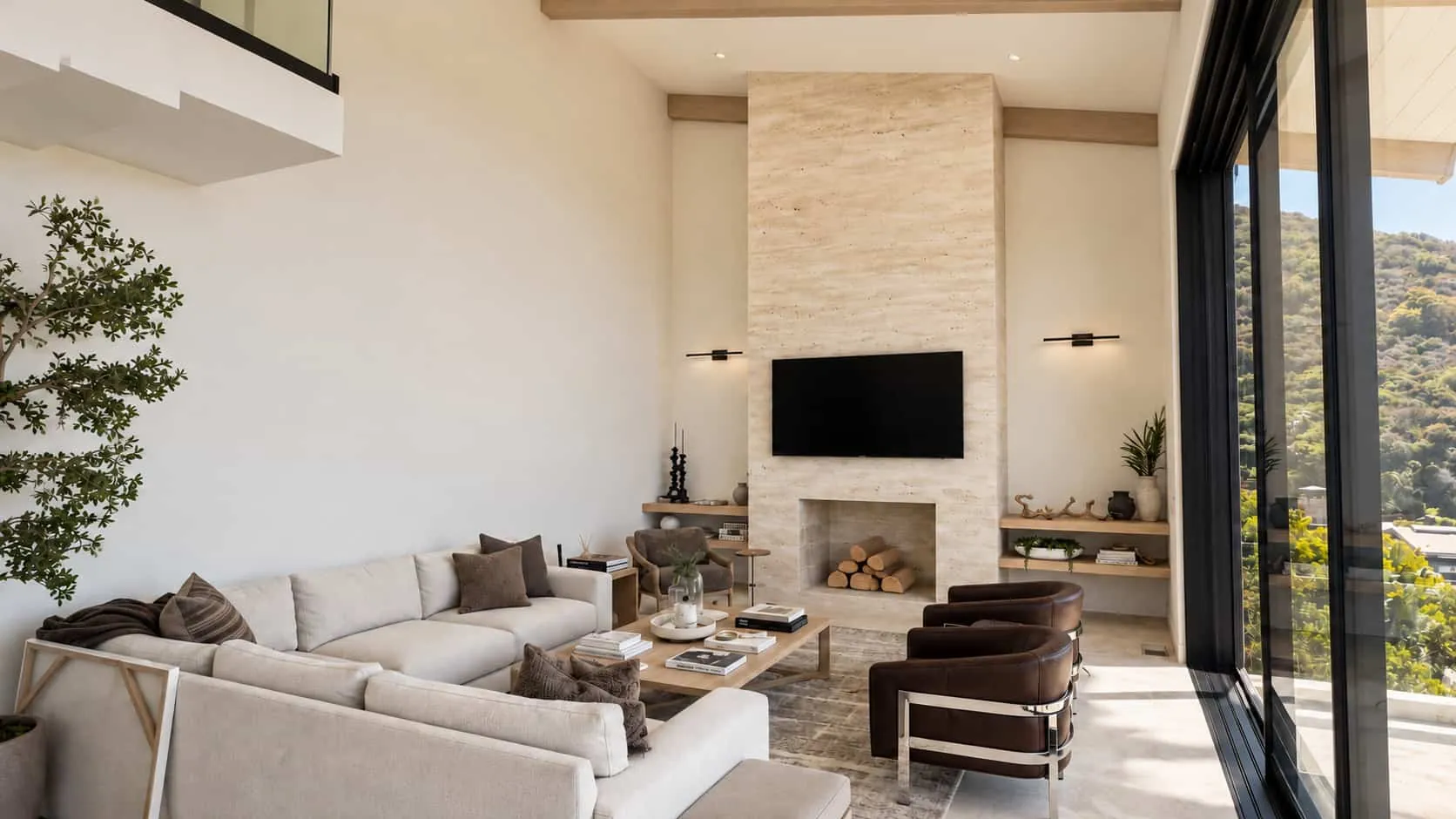 Family room with a floor-to-ceiling fireplace wall in Travertino Venetian plaster, a linen sectional and a hillside view