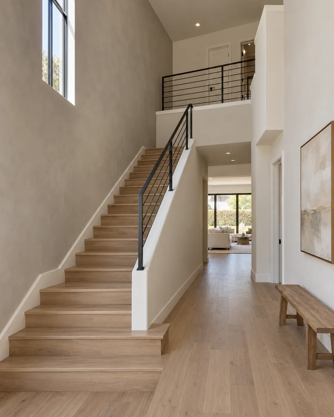 Two-story entry with a greige Roman clay stair wall, white oak stairs with a black metal railing and a tall window