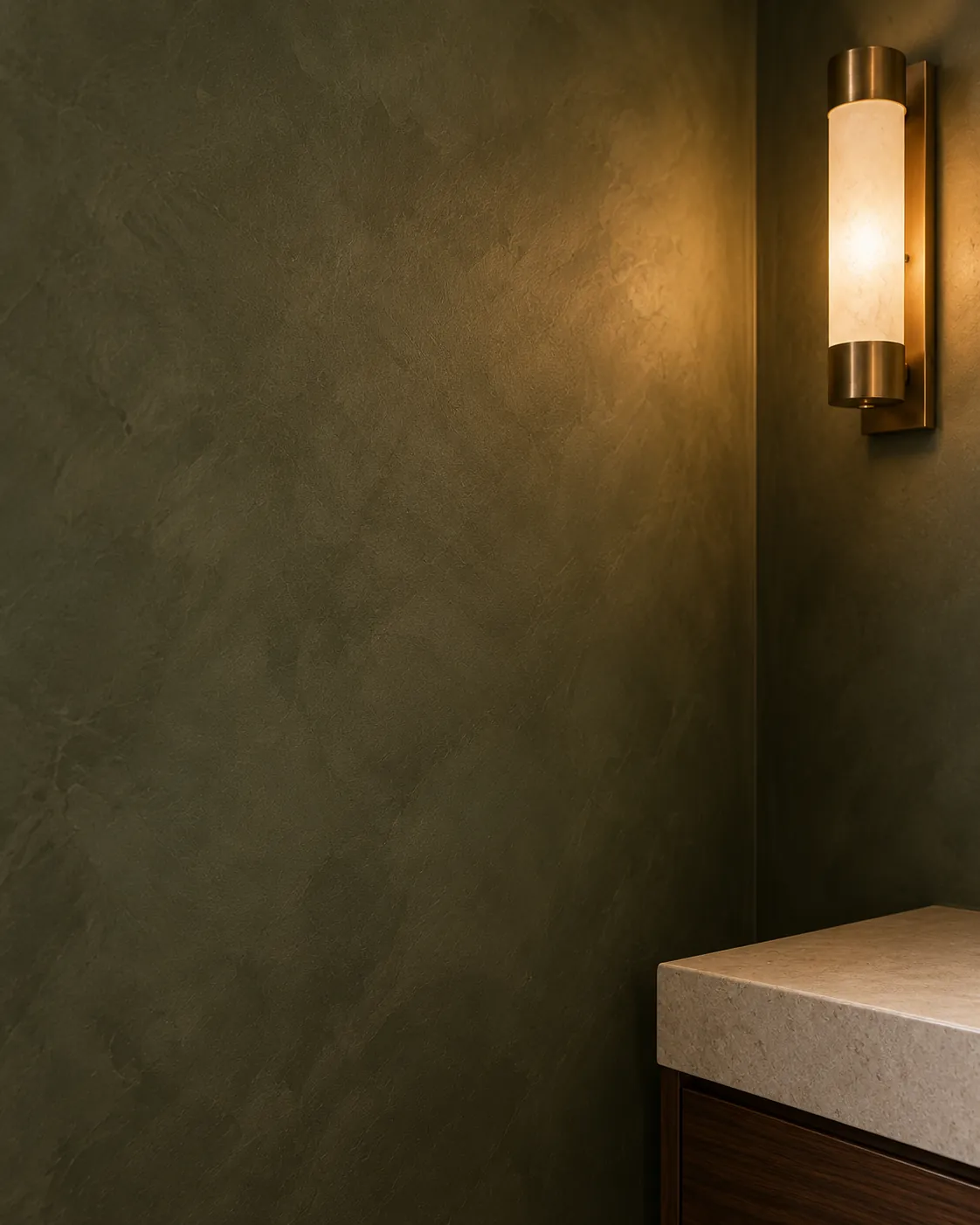 Close-up of deep olive Roman clay beside a brass and alabaster sconce, with soft cloudy shifts and a faint glow where the light grazes the wall
